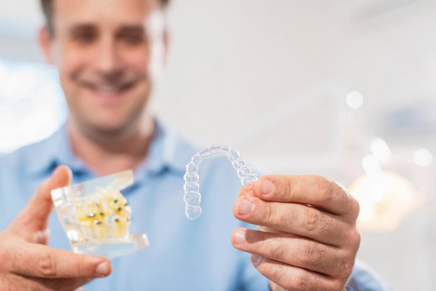 Dentist holding a clear aligner and dental model used to correct bite problems