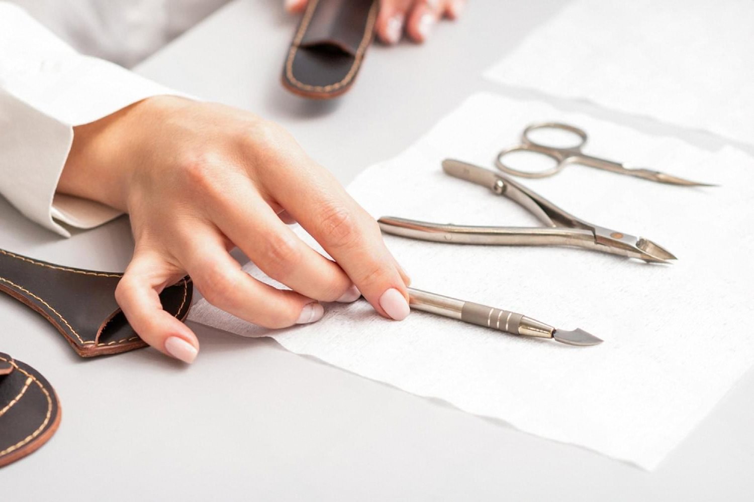 Manicurist arranging sterilised cuticle nippers and pushers on a clean salon workstation